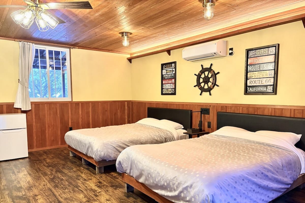 Una habitación con dos camas, paneles de madera, decoración con timón de barco y señales de la Ruta 66.