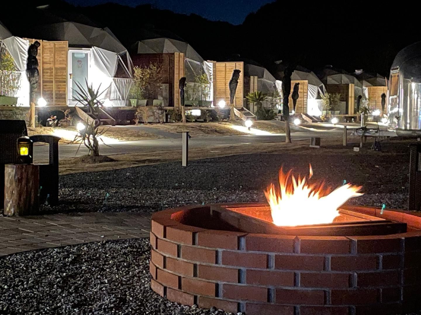 A series of dome-shaped tents with a fire pit in the foreground.