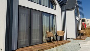 A modern house with large windows, a wooden deck, and a clear blue sky. - Oasis Village (Eforie)