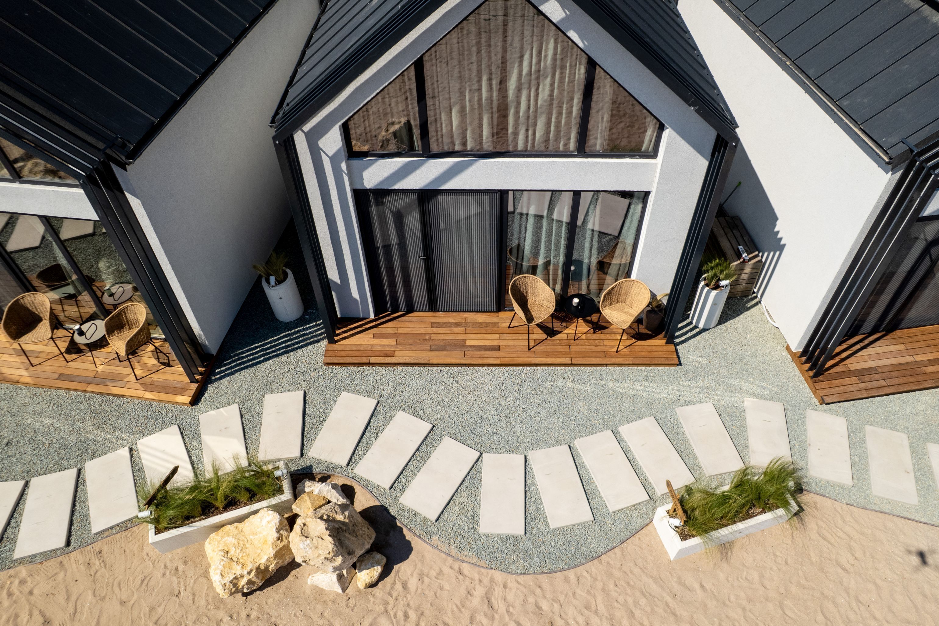 A modern house with a patio area featuring outdoor furniture and a pathway leading to the entrance.