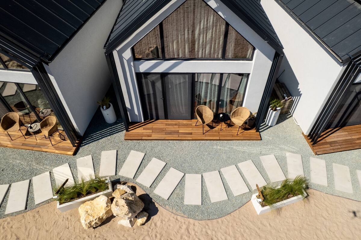 A modern house with a patio area featuring outdoor furniture and a pathway leading to the entrance.