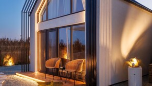 A modern house with a large glass window, a wooden deck, and a stone pathway. - Oasis Village (Eforie)