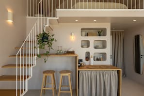 A modern interior with a staircase, wooden stools, a small table, and wall-mounted shelves. - Oasis Village (Eforie)
