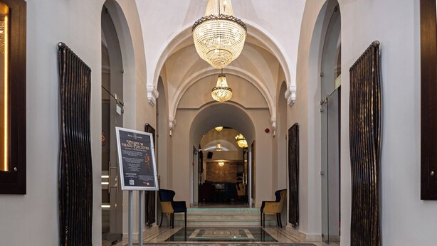 A marble-floored corridor with 'PALACE CZECHOTKI 1564' inscribed, leading to a grand archway. - Czeczotka Palace Apartments (Kraków)