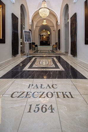 Ein von Marmor ausgelegter Korridor mit der Inschrift 'PALACE CZECHOTKI 1564', der zu einem prunkvollen Bogen führt.