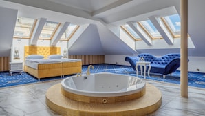 A spacious room with a large bathtub, a bed, and a blue sofa. - Czeczotka Palace Apartments (Kraków)