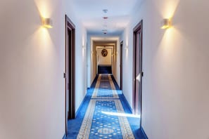A hallway with a blue carpet, light fixtures on the walls, and a door at the end. - Czeczotka Palace Apartments (Kraków)