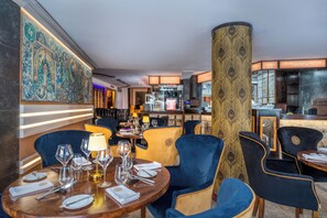 A restaurant with round tables, chairs, and a decorative wall. - Czeczotka Palace Apartments (Kraków)
