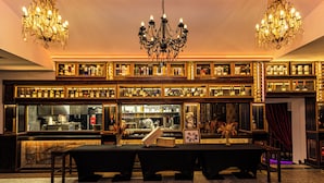A bar area with a long counter, multiple shelves of bottles, and a chandelier. - Czeczotka Palace Apartments (Kraków)