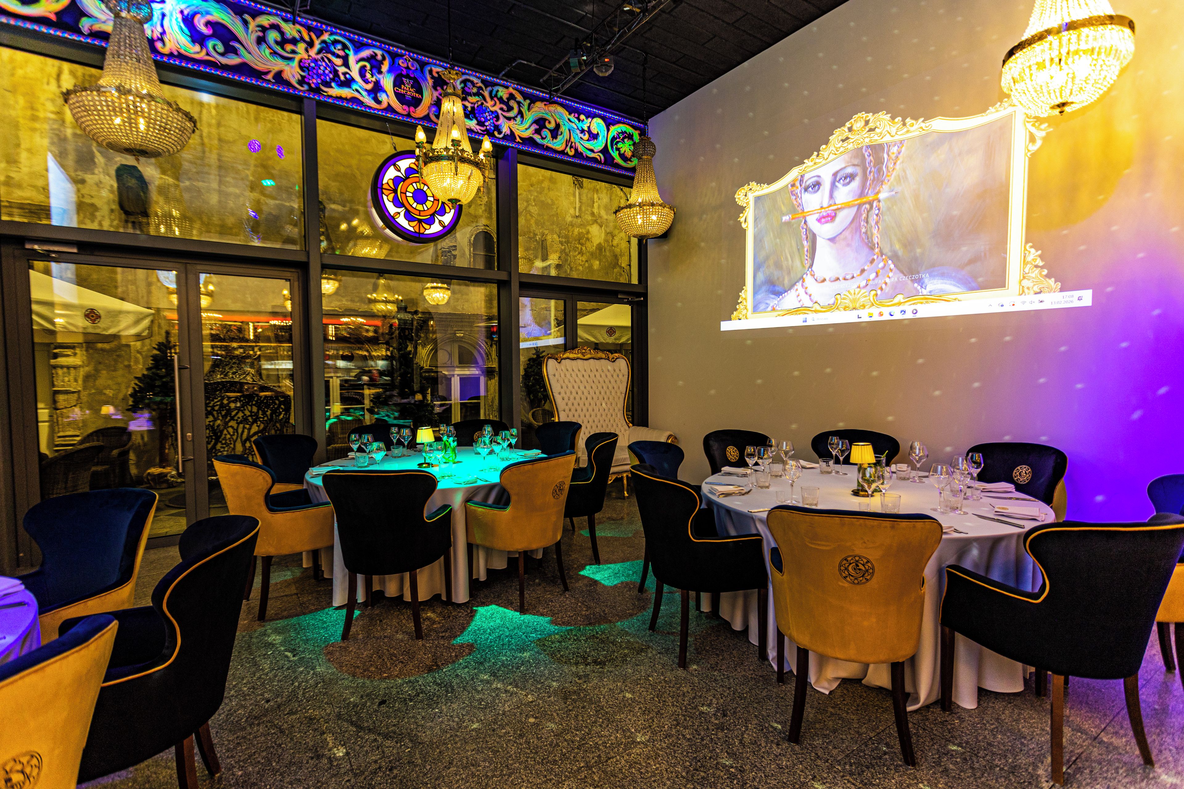 A restaurant with tables set for dining, chairs, and chandeliers.