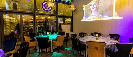 A restaurant with tables set for dining, chairs, and chandeliers.