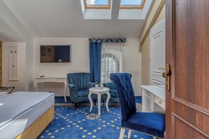 Une chambre d’hôtel comprenant un lit, un bureau, une chaise, une petite table et une armoire.