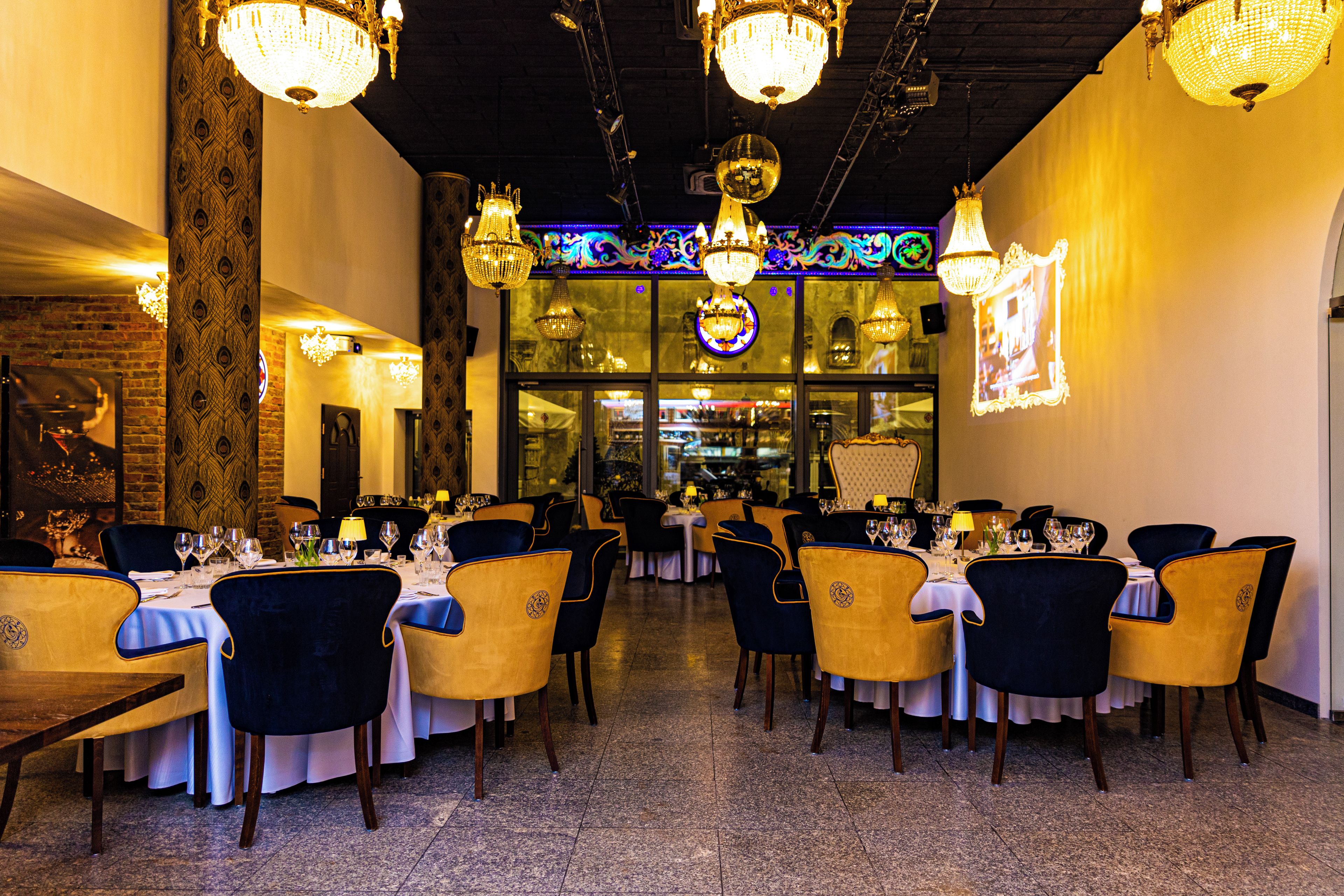 A restaurant with multiple tables, chairs, and chandeliers.