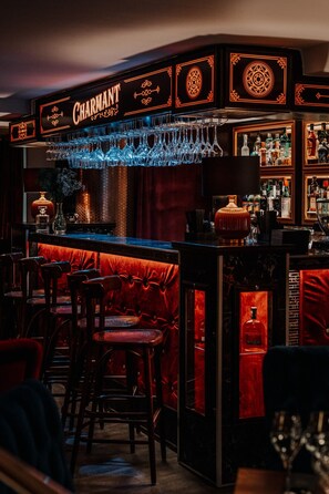 A bar area with a neon sign, bar stools, and a variety of bottles. - Czeczotka Palace Apartments (Kraków)