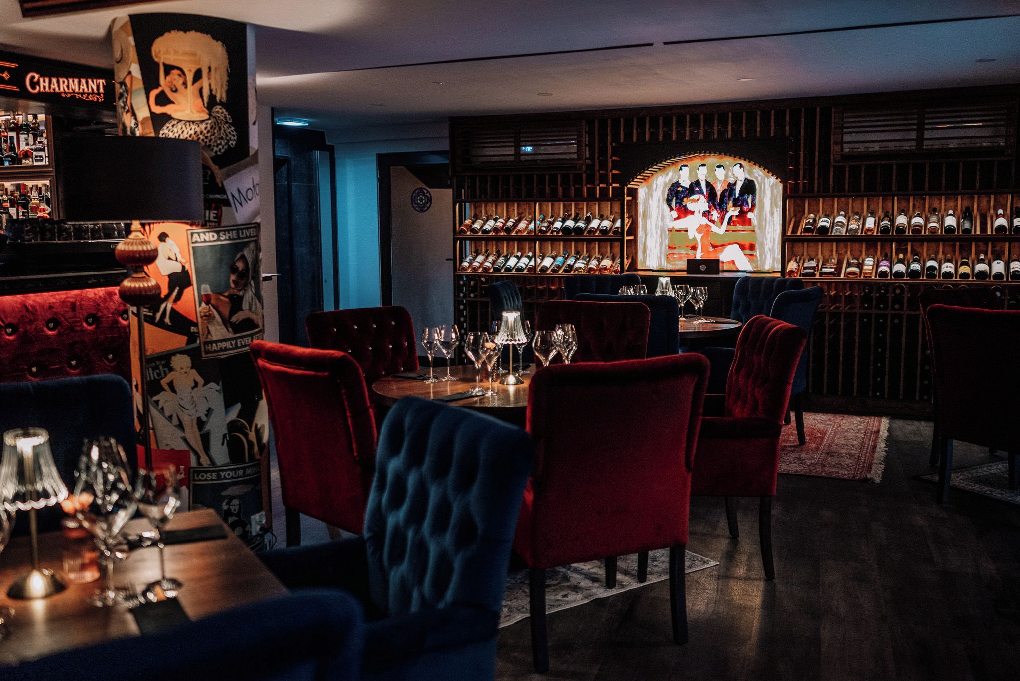 Un espace bar avec un présentoir à bouteilles de vin, des chaises à revêtement rouge et un comptoir.