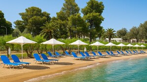 A beach with rows of blue lounge chairs and white umbrellas, a sandy shore, and a clear blue sea. - Paradise Resort Evia (Eretria)