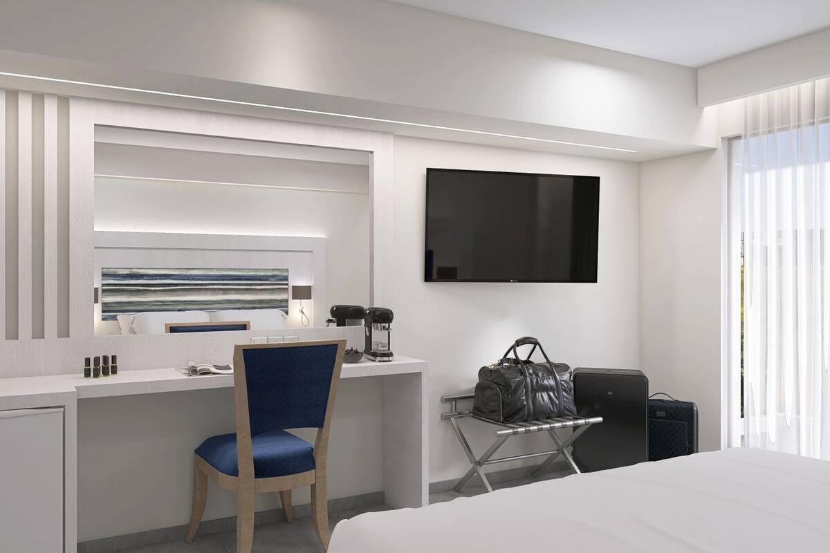 A modern hotel room with a desk, chair, TV, and a bed.