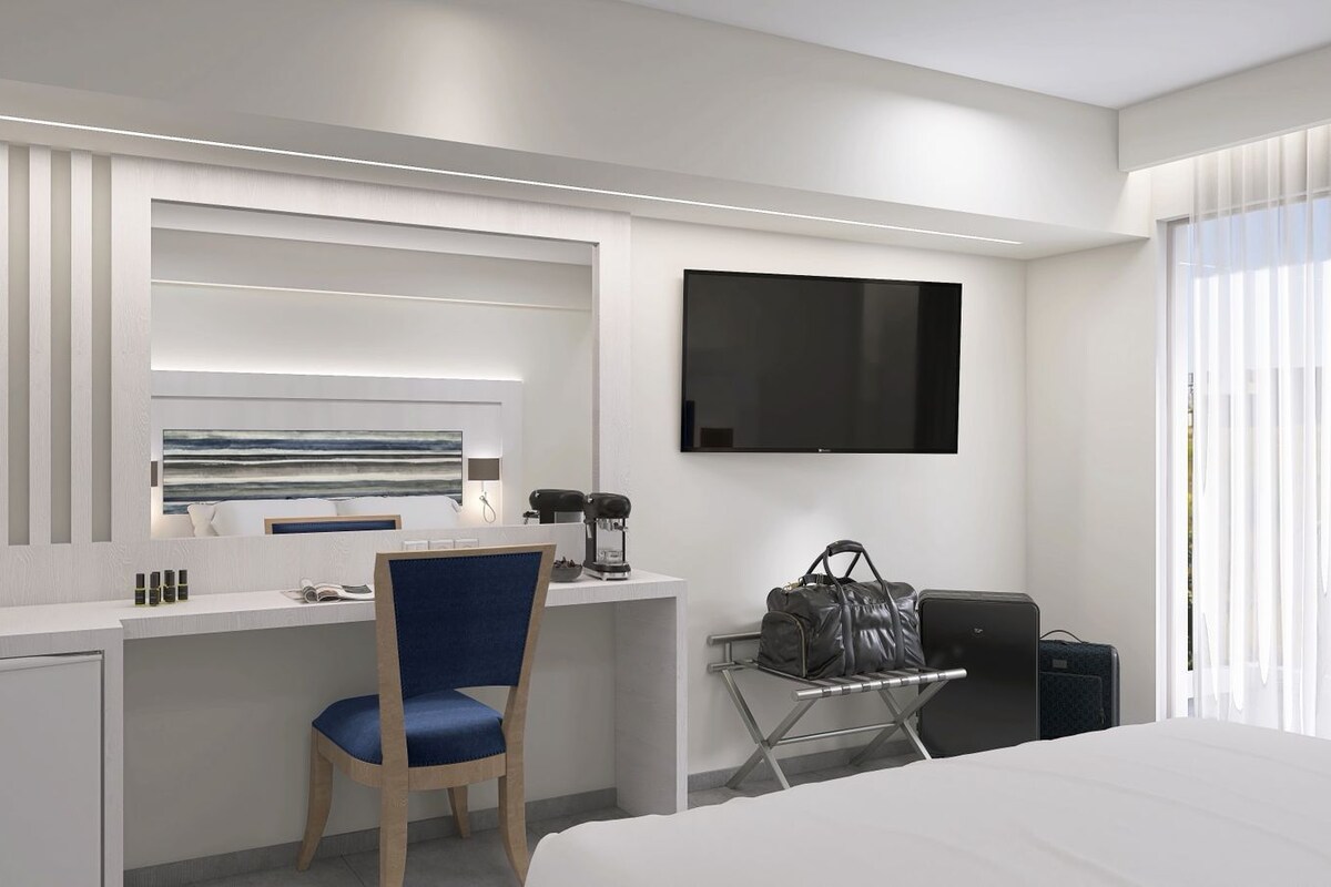 Una habitación de hotel moderna con escritorio, silla, televisor de pantalla plana y cama.