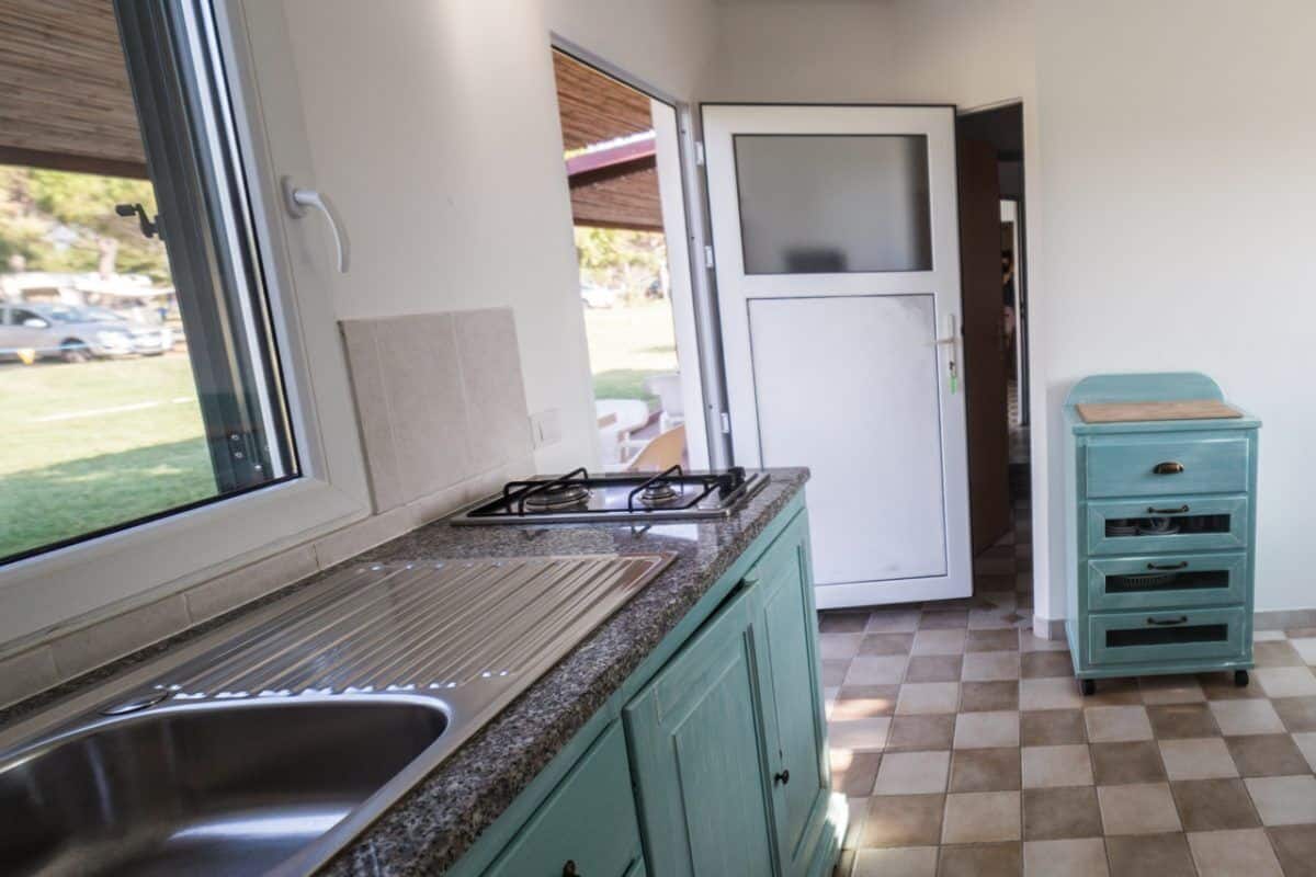 A compact kitchen with a sink, stove, and a small dining area with a table and chairs.