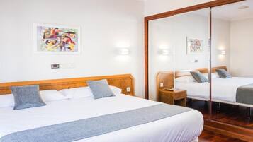 Una habitación de hotel con una cama grande, cabecero de madera, una mesita de noche, un espejo y una obra de arte colgada en la pared.
