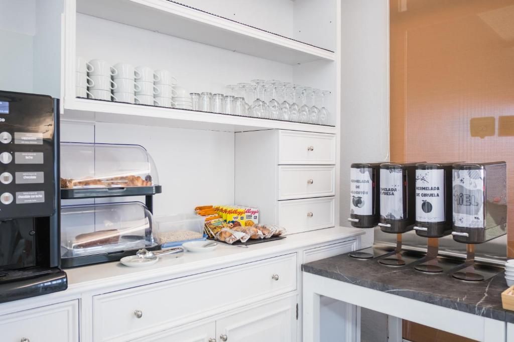 Una kitchenette con macchina del caffè, bicchieri e distributori di condimenti.