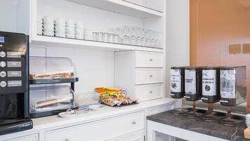 Una kitchenette con macchina del caffè, bicchieri e distributori di condimenti.