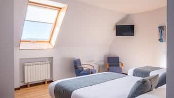 A bedroom with a skylight, a bed, a desk, two chairs, and a TV.