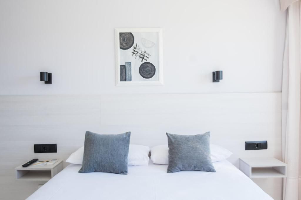 A modern hotel room with a large bed, two bedside tables, a wall-mounted artwork, and a nightstand with a remote control.