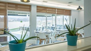 A bright room with large windows, white furniture, and potted plants. - Alda Arteixo (Abegondo)