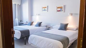 Habitación de hotel con dos camas, un escritorio y una silla.