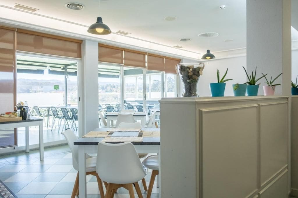Un comedor moderno con una mesa para dos personas, sillas blancas y un jarrón decorativo.