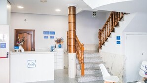A reception area with a marble staircase, a reception desk, and a wooden handrail. - Alda Arteixo (Abegondo)