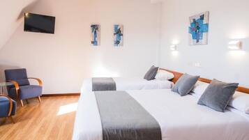 Habitación de hotel con dos camas, un televisor de pantalla plana y obras de arte en las paredes.