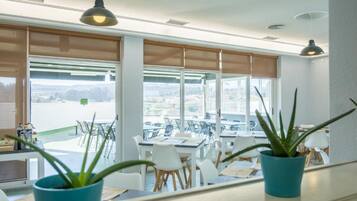 A bright room with large windows, white furniture, and potted plants.