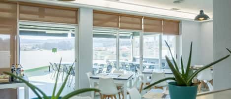 A bright room with large windows, white furniture, and potted plants.