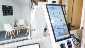 A reception area with a digital kiosk displaying the hotel name, a sign for Hotel Alda Artejo, and a payment terminal. - Alda Arteixo (Abegondo)