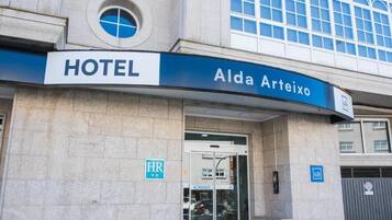 Entrada de un hotel con un cartel que dice 'HOTEL Alda Arteixo'.