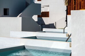 A modern architectural design with a pool area, white walls, and wooden accents. - Elion Seaside Resort (Chalcis)