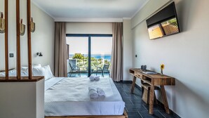 Ein Hotelzimmer mit einem großen Bett, einem Holztisch und Blick auf den Ozean.