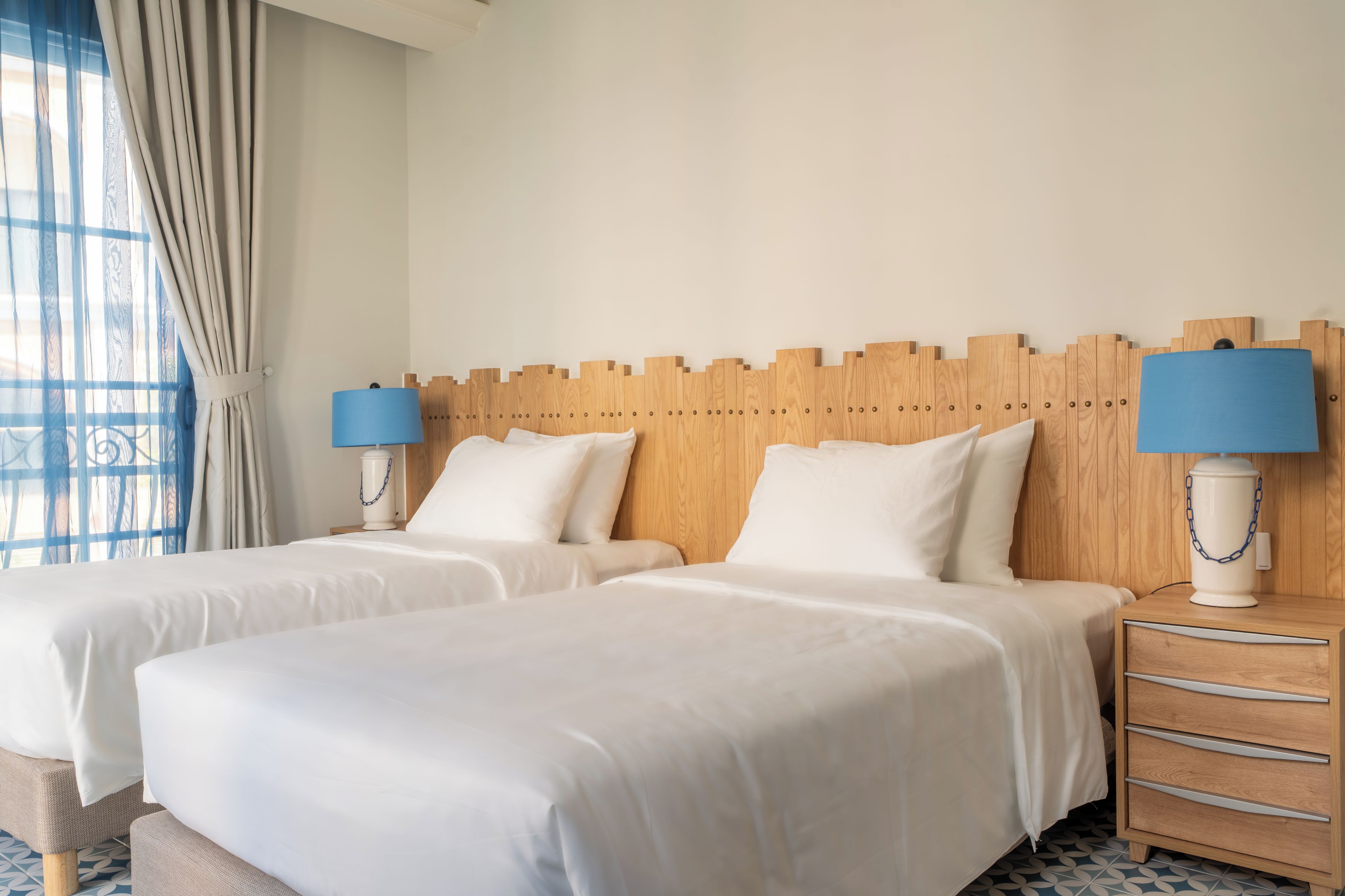 A hotel room with two beds, a wooden headboard, bedside lamps, and a nightstand.
