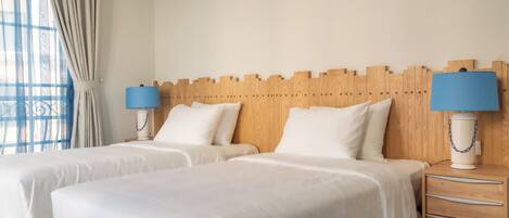 A hotel room with two beds, a wooden headboard, bedside lamps, and a nightstand.