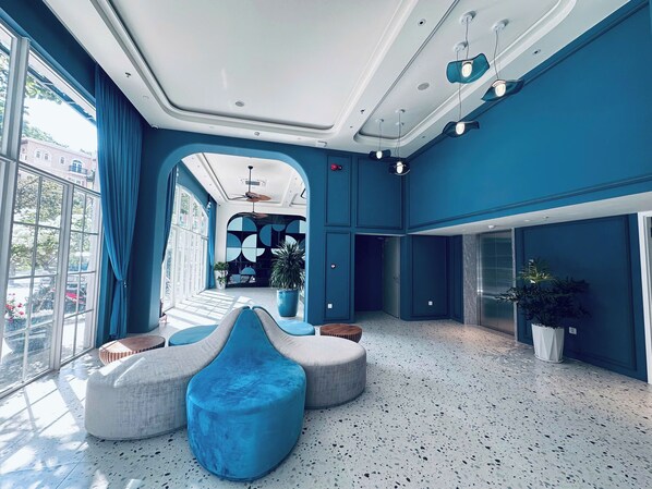 A spacious lobby with a high ceiling, large windows, and a central seating area with blue and white furniture. - Solaro Hotel & Spa (Phu Quoc)