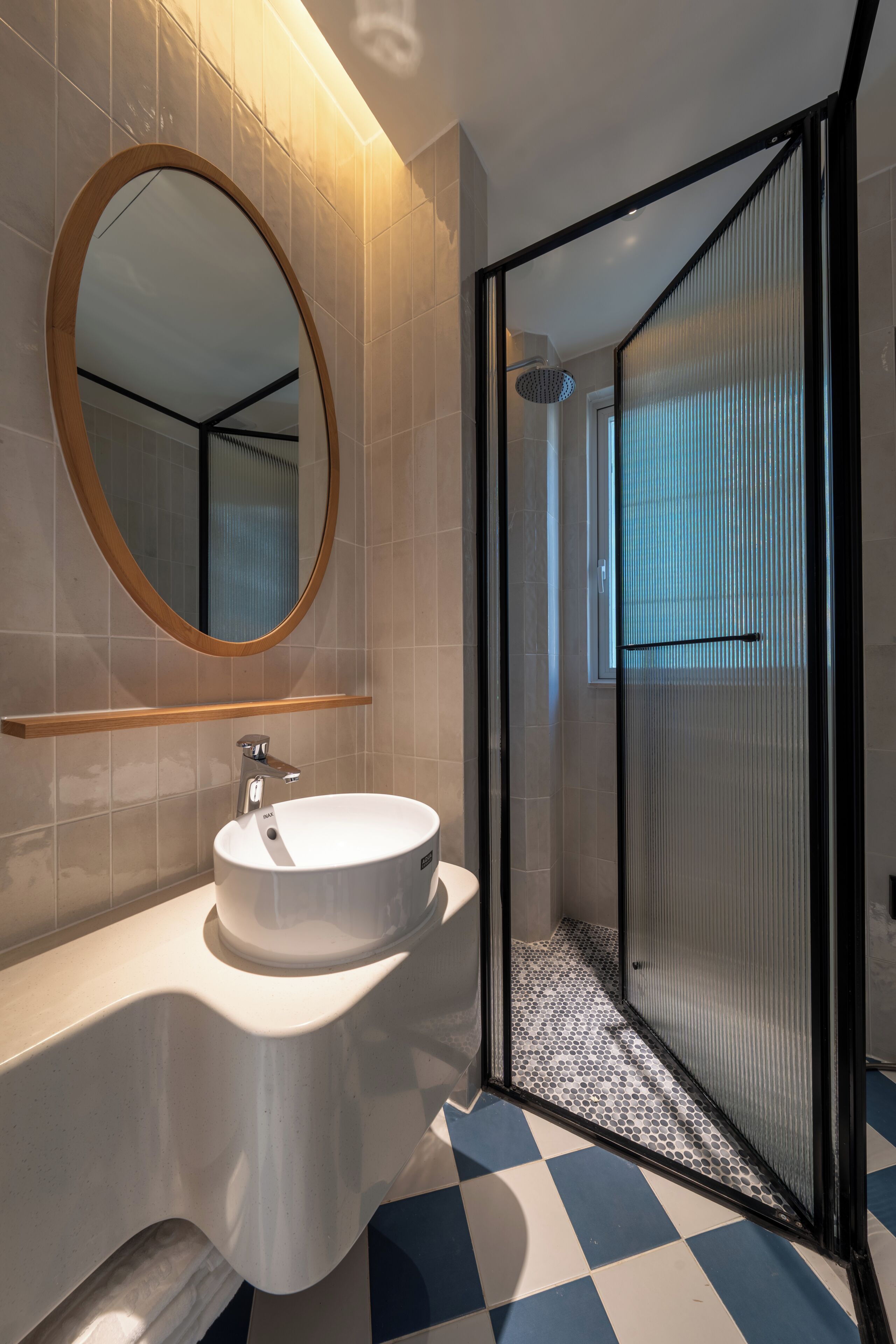 A modern bathroom with a round mirror, a white sink, and a shower enclosure.