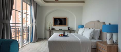 Une chambre d’hôtel comprenant un lit, une table de chevet, une lampe et un bureau avec une chaise.