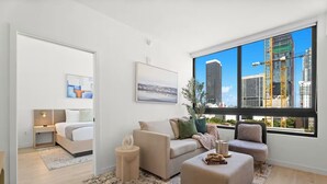 Ein modernes Wohnzimmer mit einem Bett, einem Sofa, einem Couchtisch und einem großen Fenster mit Blick auf die Stadt.
