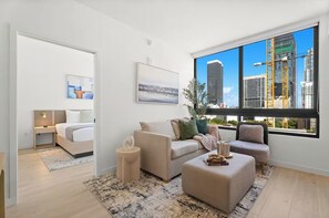 A modern living room with a bed, a sofa, a coffee table, and a large window with a city view. - Stay in the Heart of Miami + Free parking (Miami)