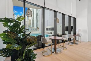 A modern hotel room with large windows, a pool view, and a seating area with round tables and chairs. - Stay in the Heart of Miami + Free parking (Miami)