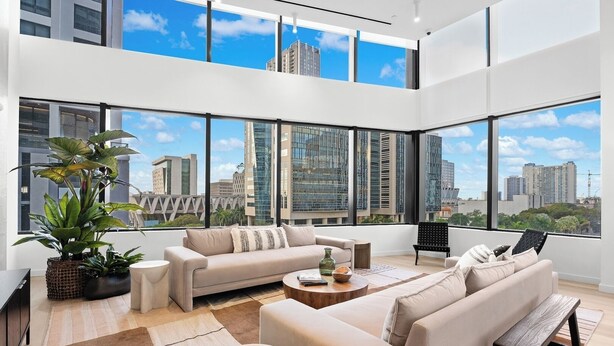 Ein modernes Wohnzimmer mit einer Couch, einem Couchtisch und einem großen Fenster mit Blick auf die Stadt.