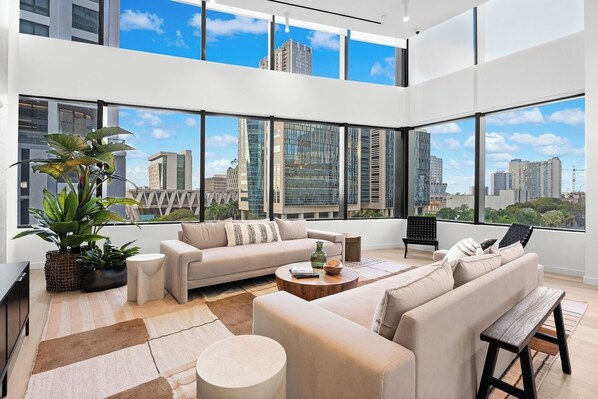 A modern living room with a sofa, coffee table, and a large window offering a city view. - Stay in the Heart of Miami + Free parking (Miami)