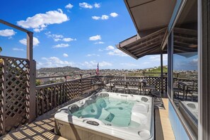 Eine Dachterrasse mit Whirlpool, Sitzgelegenheiten im Freien und Blick auf die Stadt.